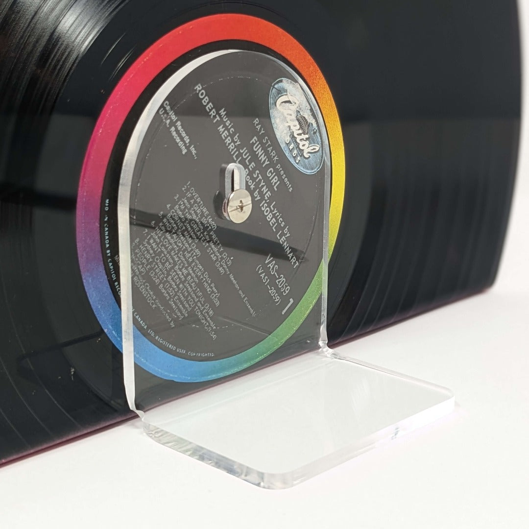 A DIY upcycled vinyl record shelf made from a stack of vintage vinyl records. On top of the shelf, there is an acrylic square serving as a standalone display platform. It is held in place by a Chicago screw